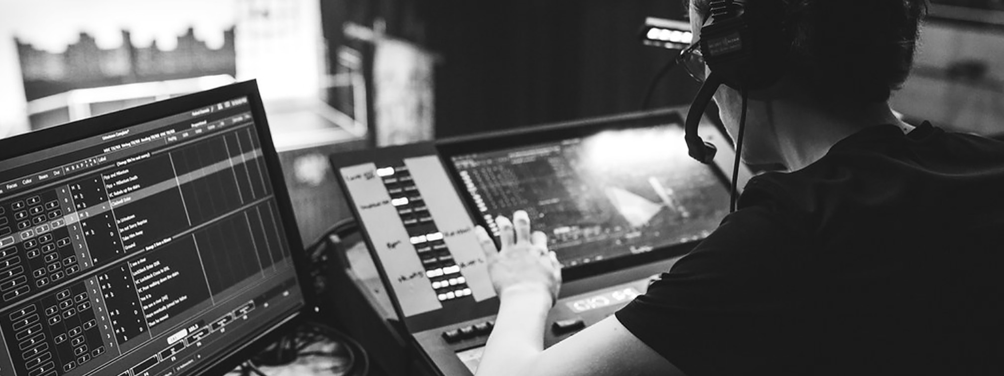 A black & white image of a man using a mixing desk and computer