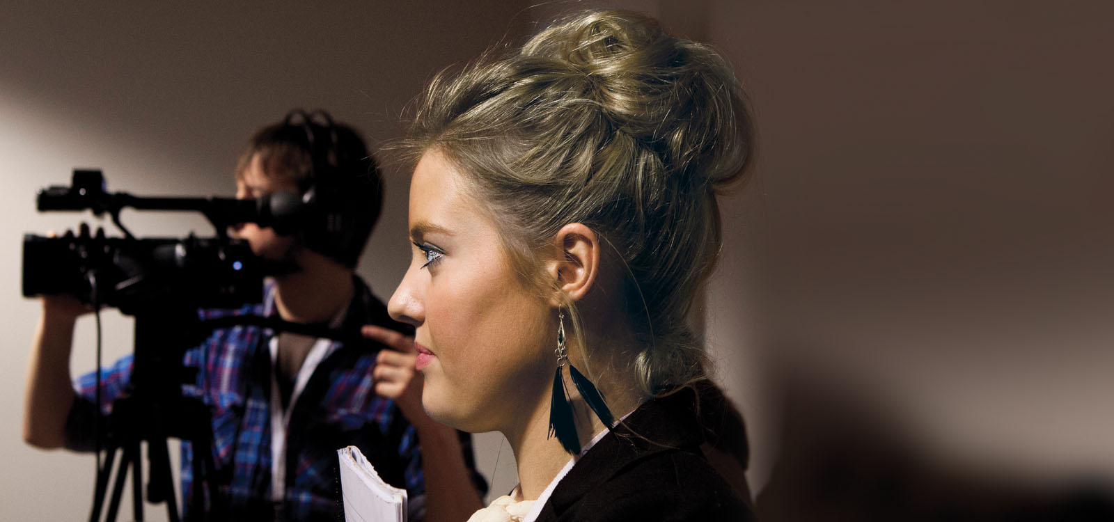 Female student standing next to a video camera during a mock press conference 