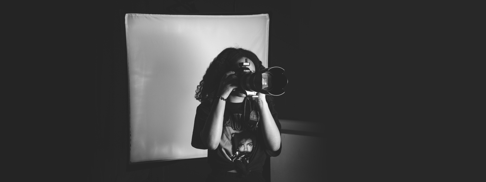 Black and white image of a female student with a camera in the photography studio