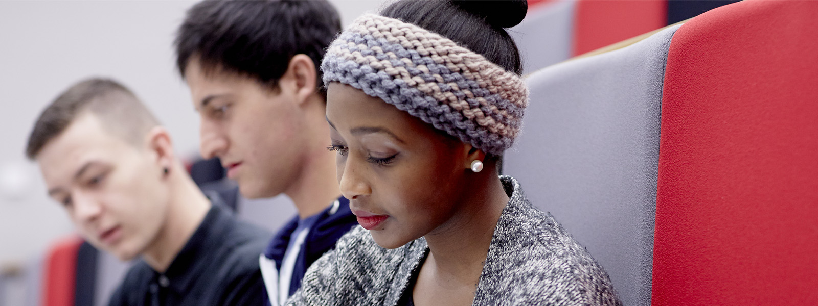 Three students sat together and taking notes in a lecture 
