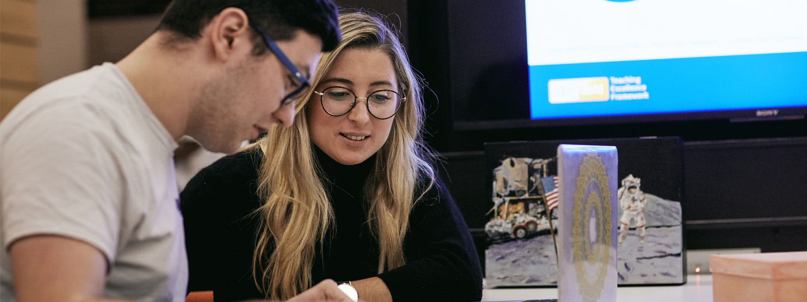 Two students chatting in front of a laptop