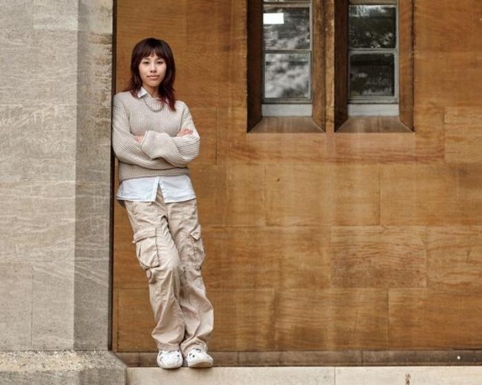 A student leaning against a post outside a historic building