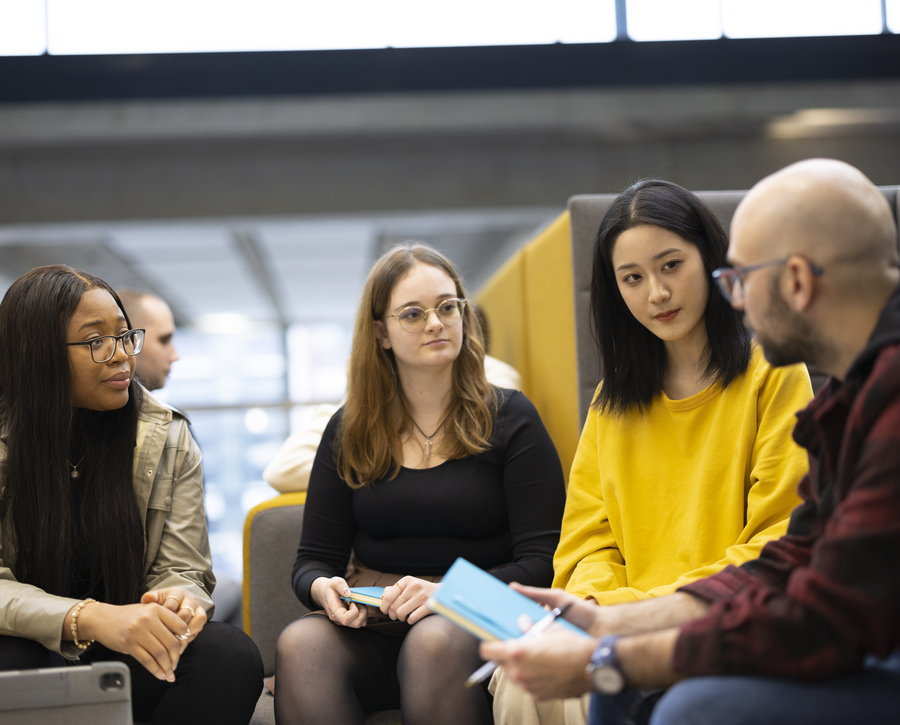 four students sitting around a coffee table in discussion