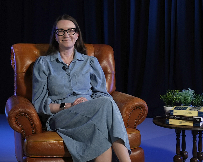 A woman in a blue dress sat in a brown chair