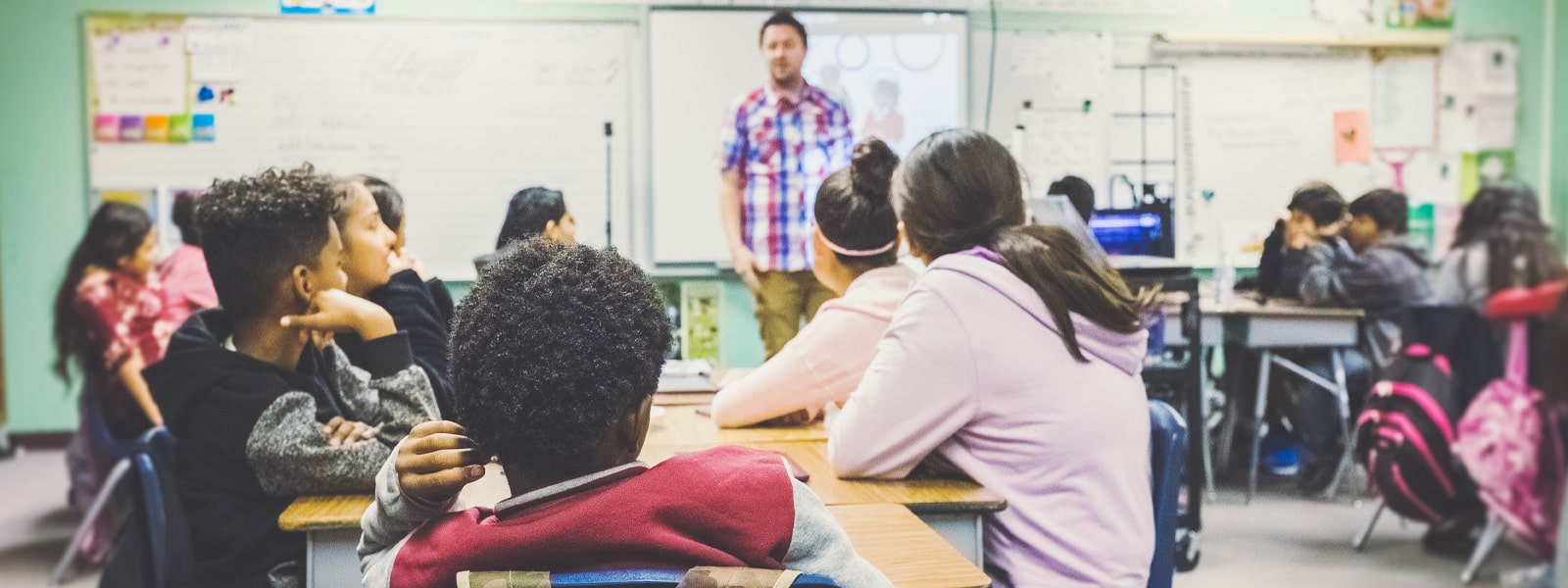 A teacher standing at the front of a classroom full of school pupils