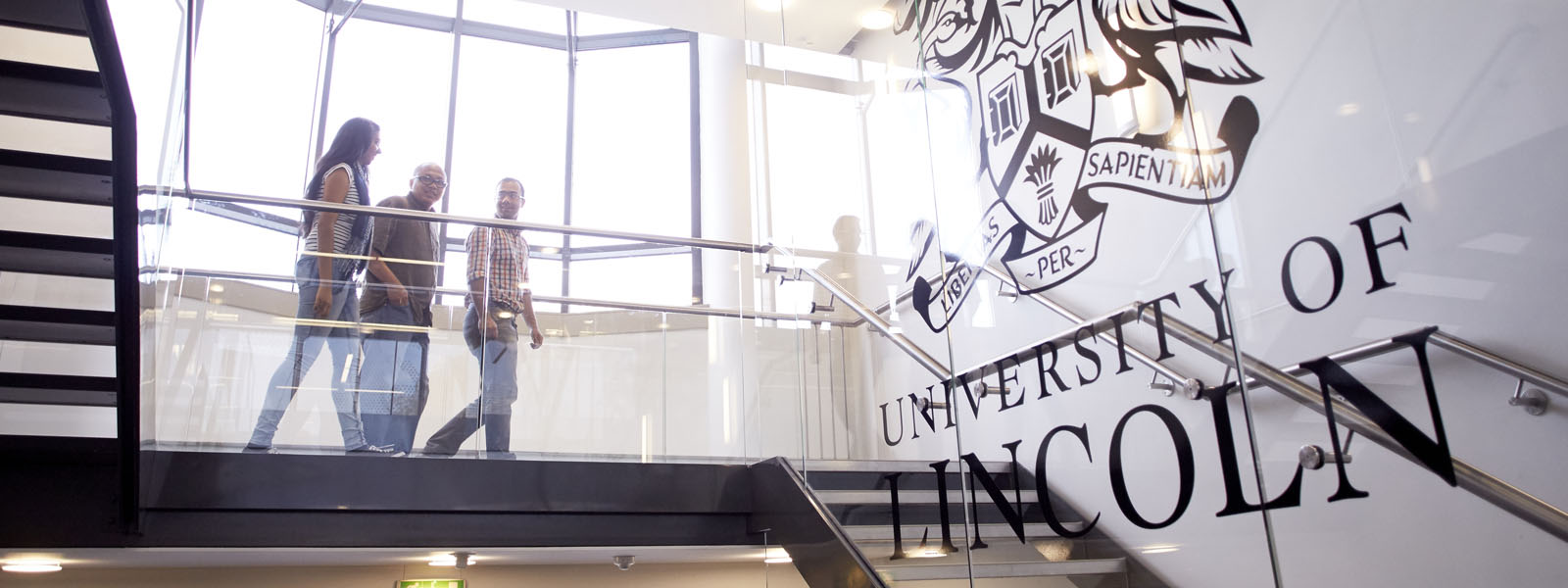 A group of academics walking on the landing of a University of Lincoln building