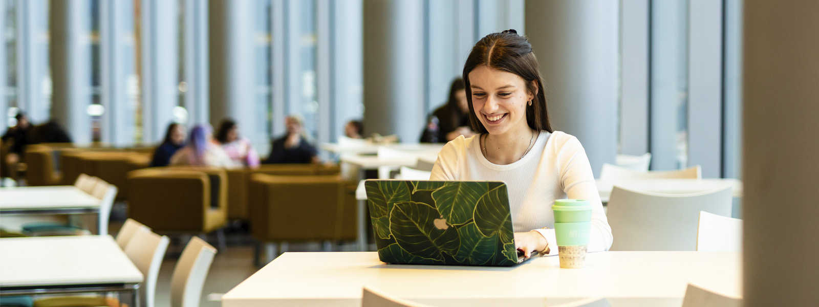 A student sat working on a laptop on campus