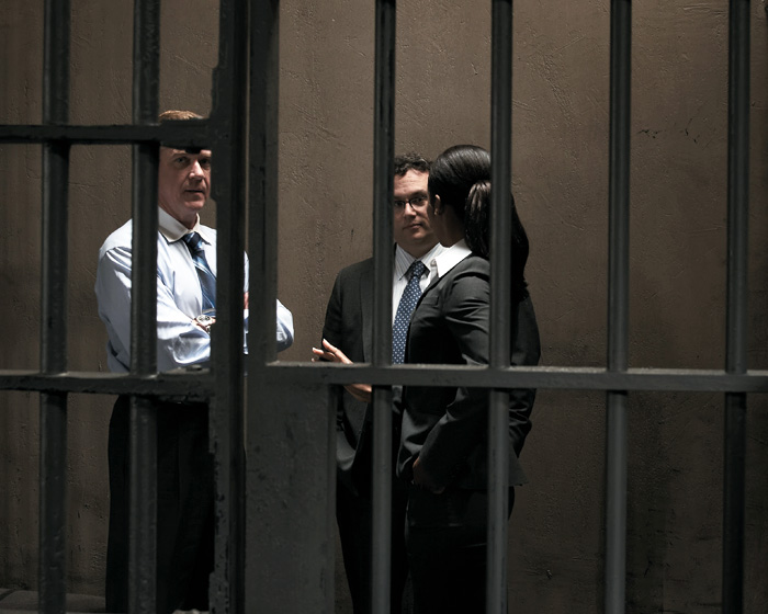 Three people talking behind prison bars