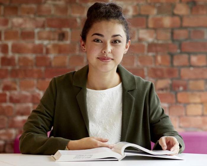 A student looking to camera in front of a brick wall