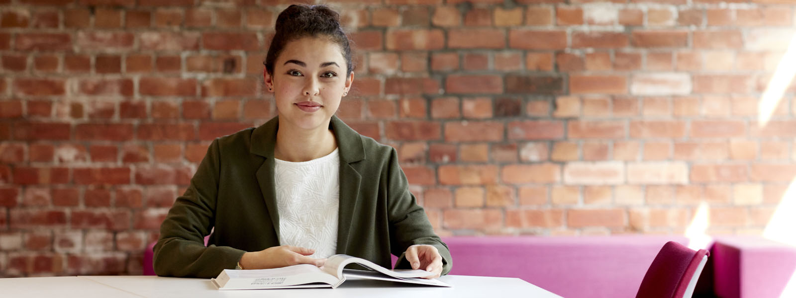 A student sat at a desk in the library reading a book