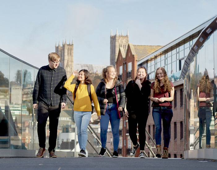 Students walking over bridge with Lincoln Cathedral in the background