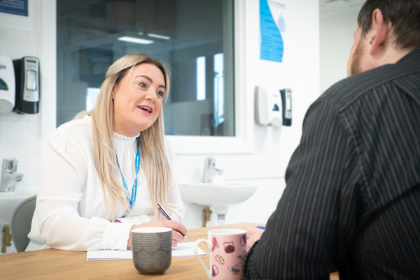 Someone sat talking to another person whilst taking notes