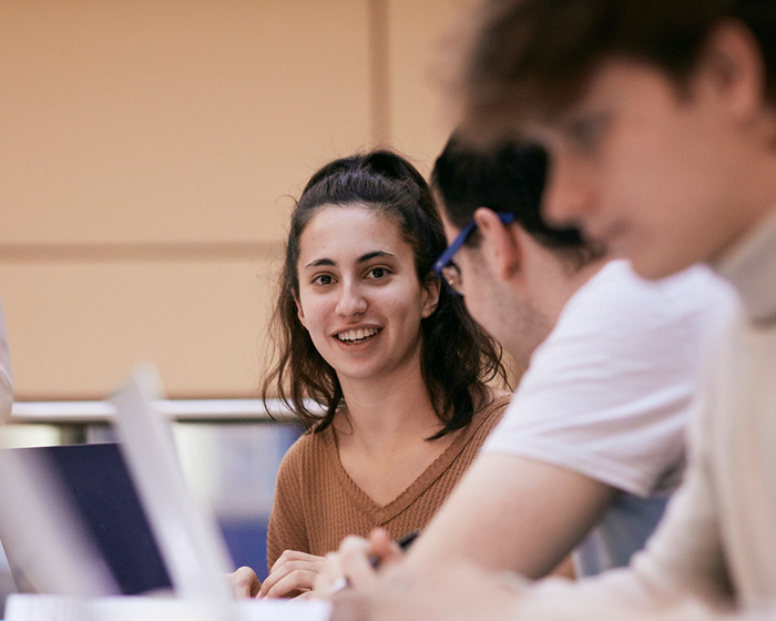 Three students sat down and working on laptops