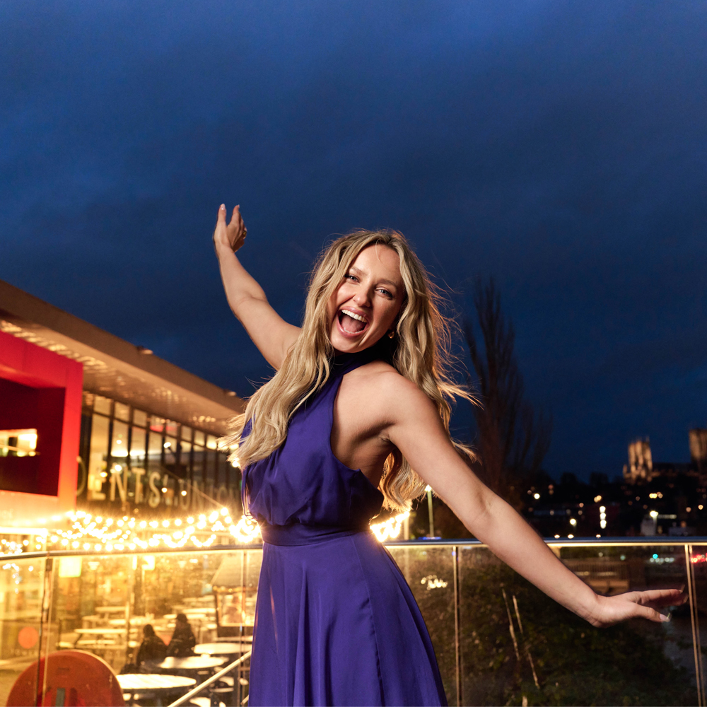 A woman standing in front of a city backdrop at night